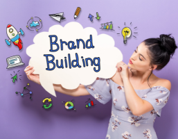 A girl holding a brand-building cloud poster with various branding icons around it to boost brands