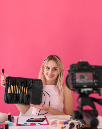 Best Brand Video Film Production Company in Coimbatore A woman holding a digital camera and makeup brushes, preparing to start her video business.